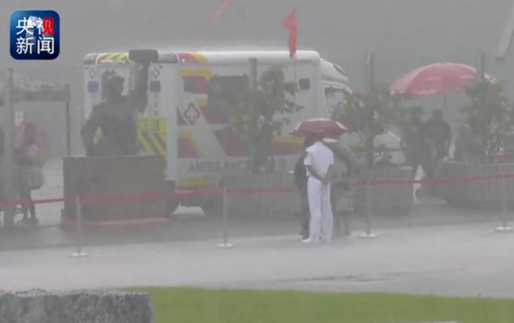Hong Kong citizen holds umbrella for PLA guard in rainstorm