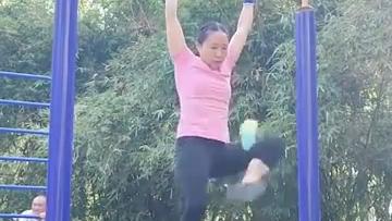 Woman kicks shuttlecock while hanging on bar