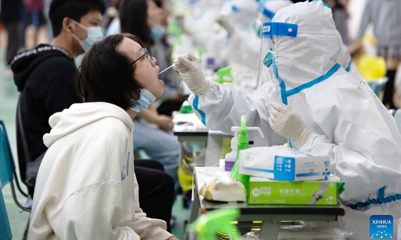 A medical worker takes a swab sample from a student for nucleic acid test at a university in Qingpu District of east China's Shanghai, March 14, 2022. Medical workers from the Xianghuaqiao community medical service center in Qingpu District of Shanghai joined the battle against the recent COVID-19 resurgence. They have collected more than 56,000 samples for nucleic acid testing since the latest resurgence in March.(Photo: Xinhua)
