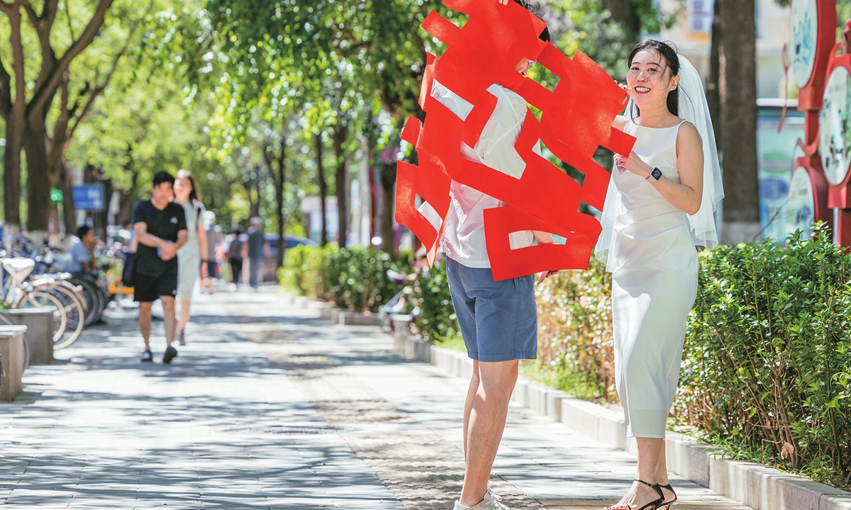 Newlyweds hold a giant paper cutting shaped as the Chinese character xi or