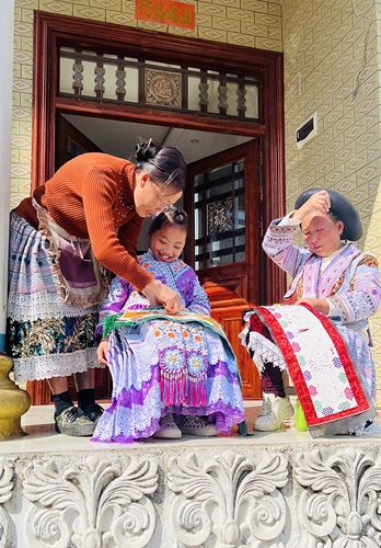 A Miao ethnic woman (left) teaches her grandchild (center) how to do Miao embroidery in Xiongdong village, Qianxi, Southwest China's Guizhou Province. Photo: Courtesy of Luo Yang
